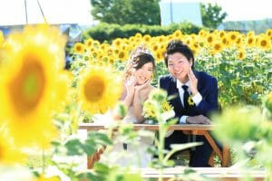 内灘町で満開のひまわりを背景に笑顔の新郎新婦様