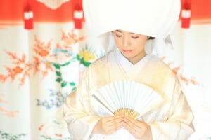 花嫁のれんを背景に綿帽子を被る新婦様