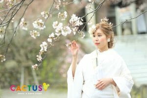 金沢市内の卯辰神社境内にて、桜の枝を触る新婦様